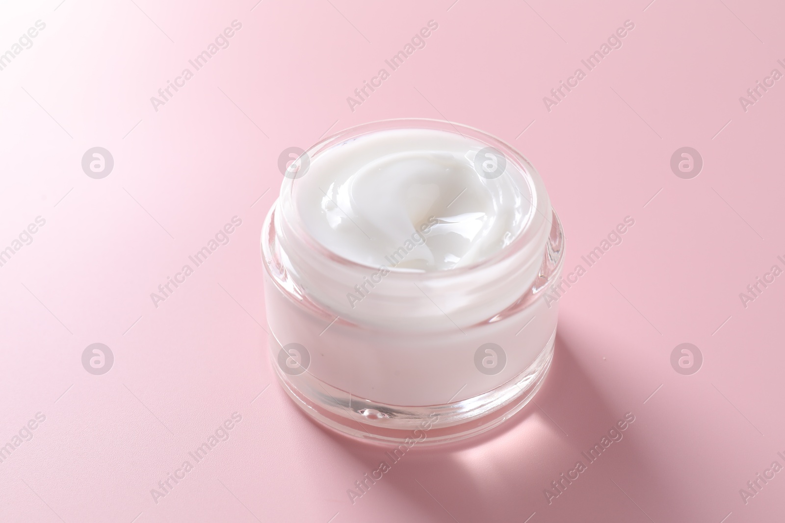 Photo of Face cream in jar on pink background, closeup