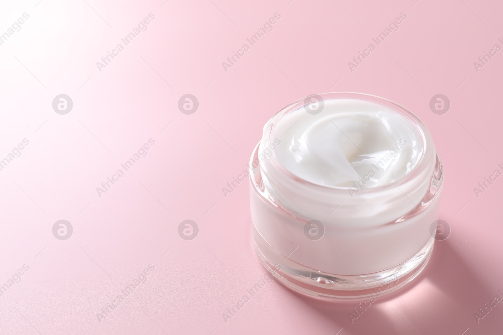 Photo of Face cream in jar on pink background, closeup. Space for text