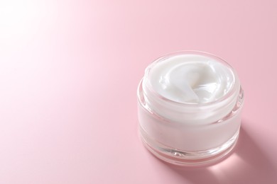 Photo of Face cream in jar on pink background, closeup. Space for text