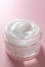 Face cream in jar on pink background, closeup