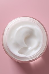 Face cream in jar on pink background, top view