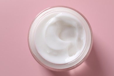 Photo of Face cream in jar on pink background, top view