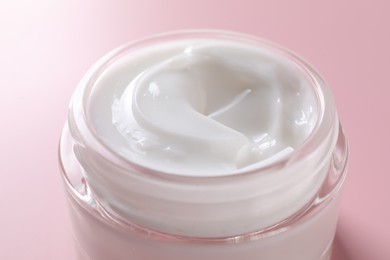 Photo of Face cream in jar on pink background, closeup