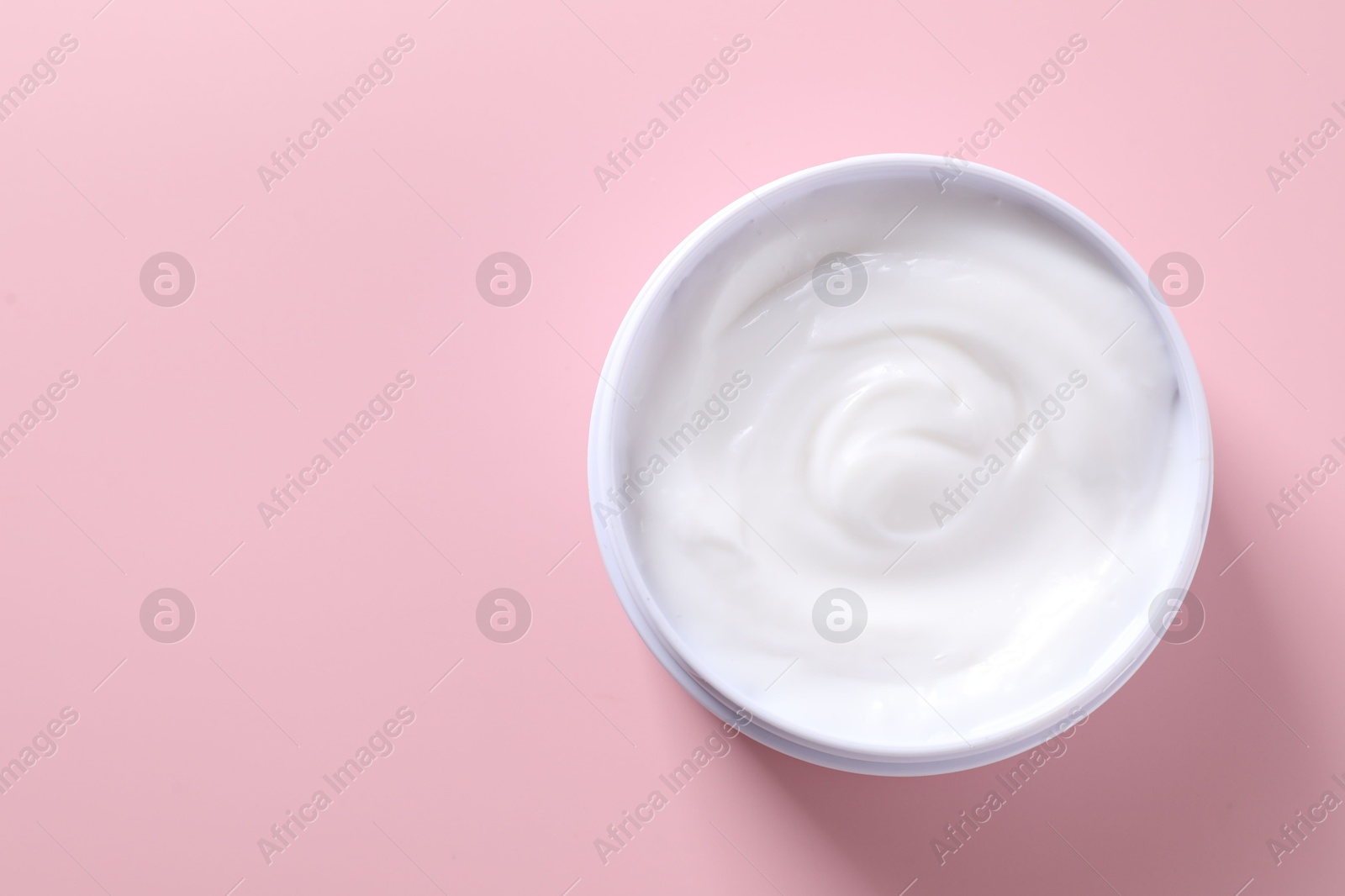 Photo of Face cream in jar on pink background, top view. Space for text