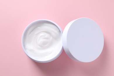 Face cream in jar on pink background, top view