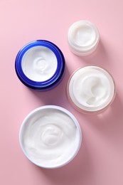 Face cream in jars on pink background, flat lay