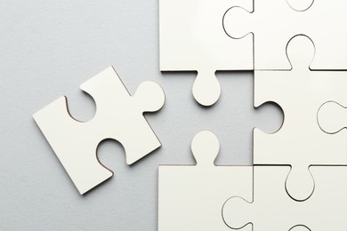 White puzzle pieces on grey background, top view