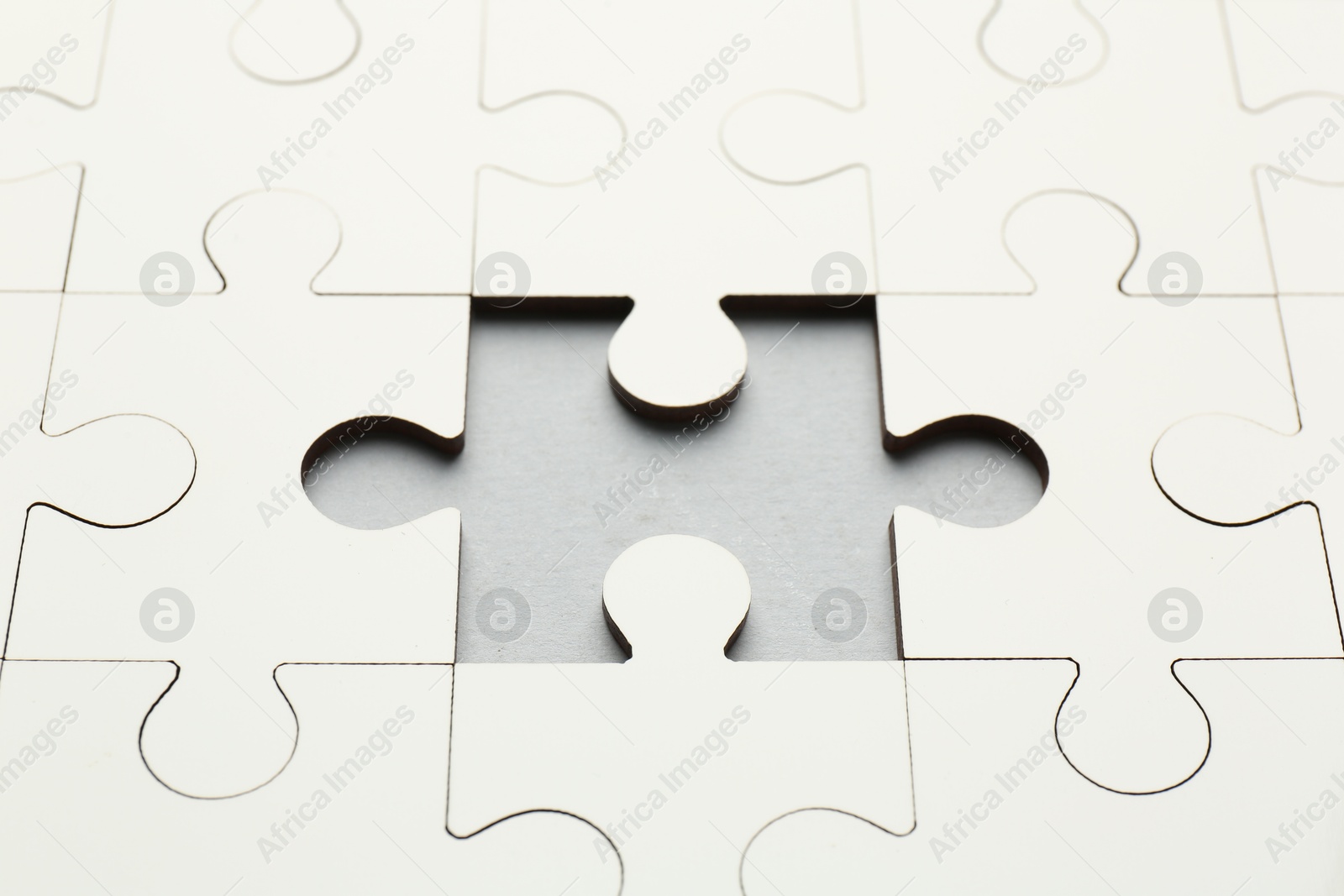 Photo of White puzzle with missing piece on grey background, closeup