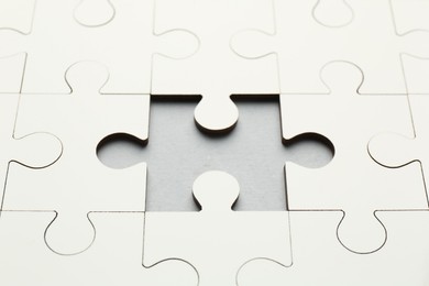 Photo of White puzzle with missing piece on grey background, closeup