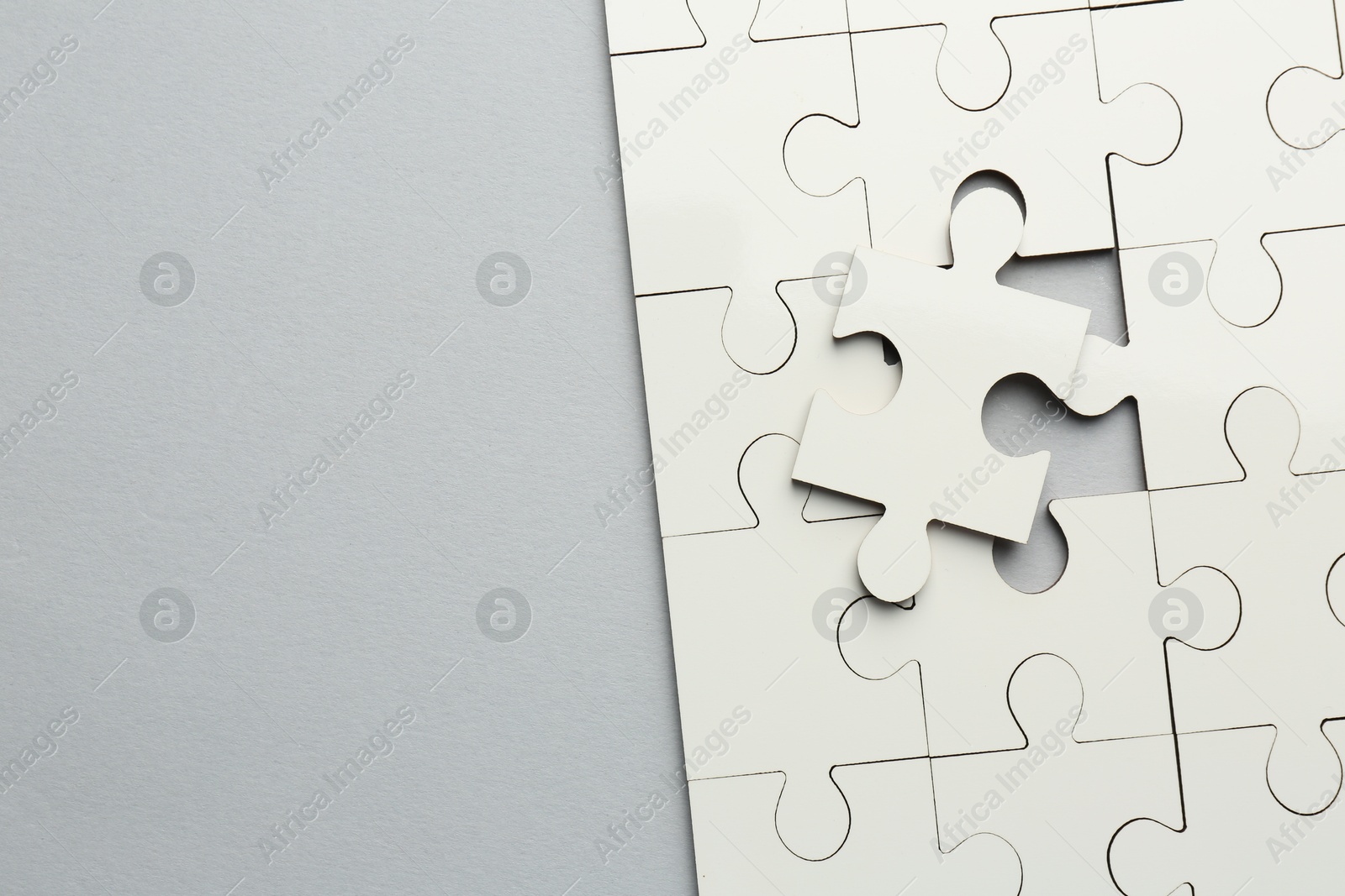 Photo of White puzzle pieces on grey background, top view. Space for text