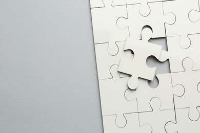 Photo of White puzzle pieces on grey background, top view. Space for text