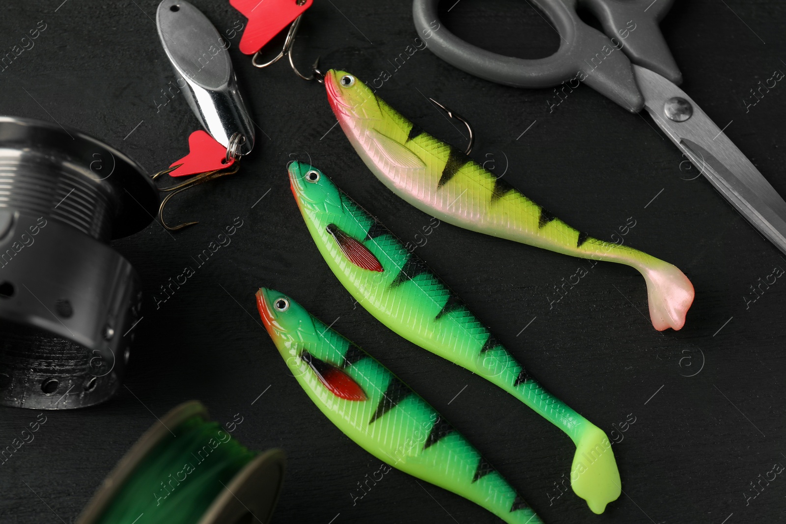 Photo of Fishing tackles, spinning reel, line and scissors on grey wooden table, closeup