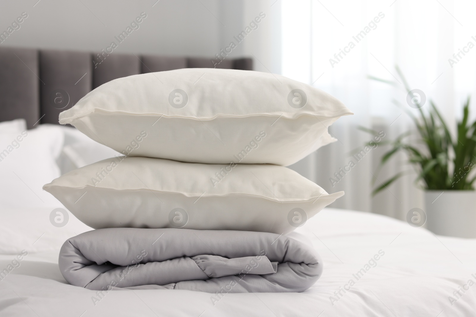 Photo of Soft pillows and duvet on bed at home