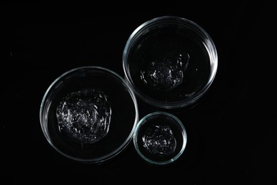 Photo of Petri dishes with samples on black mirror surface, top view