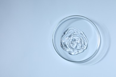 Petri dish with sample on light blue background, top view. Space for text