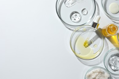 Petri dishes with different cosmetic products on white background, top view. Space for text