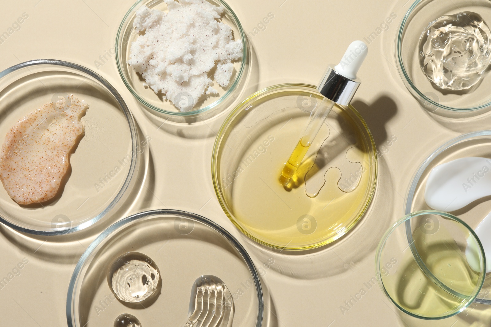 Photo of Petri dishes with different cosmetic products on beige background, flat lay