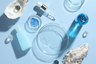 Photo of Petri dishes with cosmetic product, pipette and seashells on light blue background, flat lay