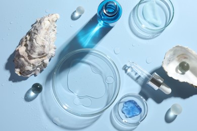 Photo of Petri dishes with cosmetic product, pipette and seashells on light blue background, flat lay