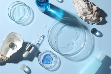 Photo of Petri dishes with cosmetic product, pipette and seashells on light blue background, flat lay