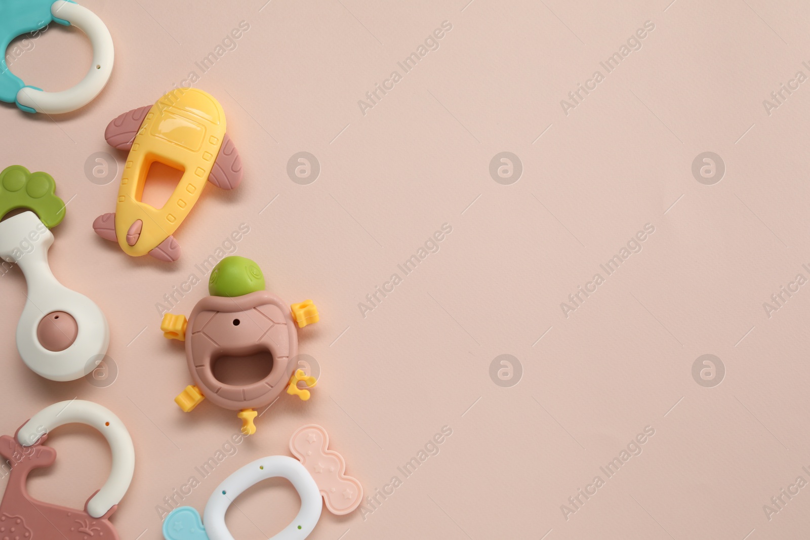 Photo of Colorful rattles on beige background, flat lay with space for text. Baby accessories