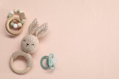 Photo of Wooden rattles and pacifier on beige background, flat lay with space for text. Baby accessories