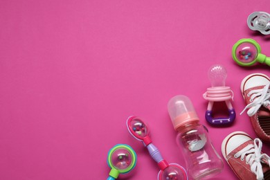 Colorful rattles, bottle, baby shoes and pacifiers on pink background, flat lay. Space for text