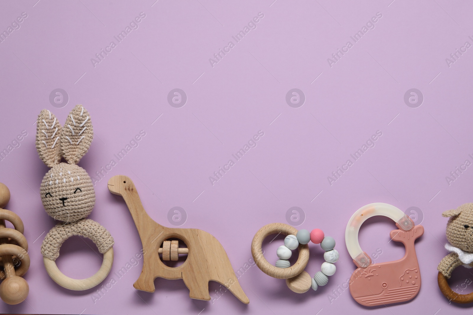 Photo of Colorful rattles on violet background, flat lay with space for text. Baby accessories