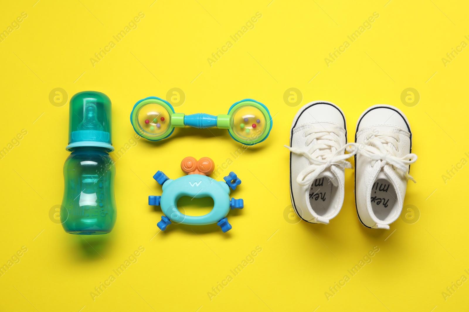 Photo of Colorful rattle and baby accessories on yellow background, flat lay