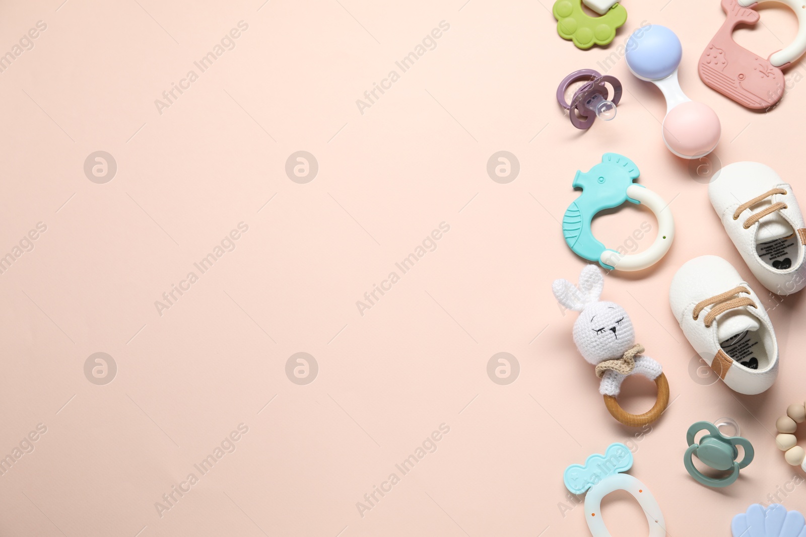 Photo of Different baby rattles and booties on beige background, flat lay. Space for text