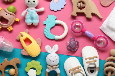 Different baby rattles and booties on color background, flat lay