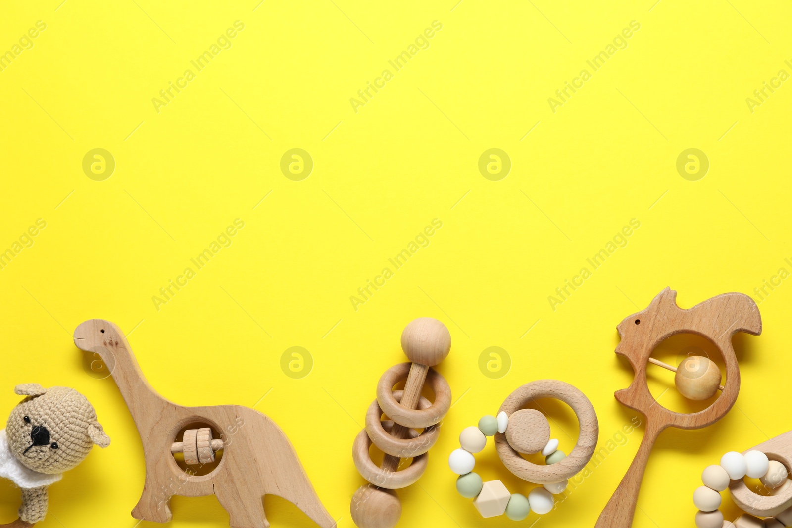 Photo of Different baby rattles on yellow background, flat lay. Space for text