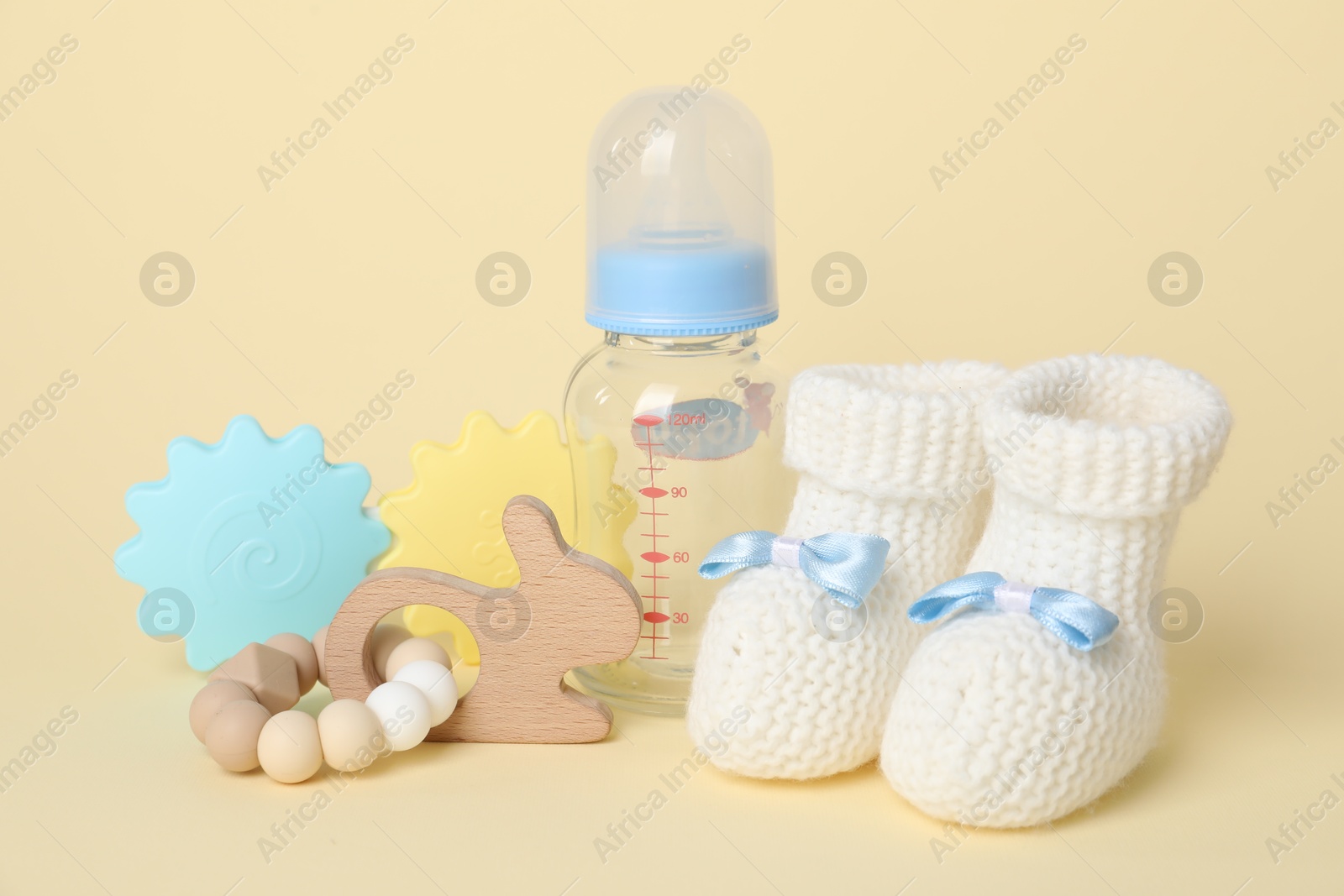 Photo of Baby toys, booties and bottle on beige background