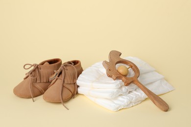 Photo of Baby rattle, booties and diapers on beige background