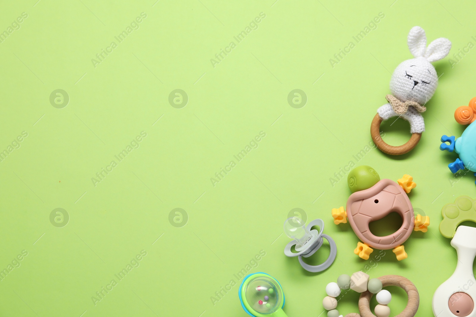 Photo of Different baby rattles on green background, flat lay. Space for text