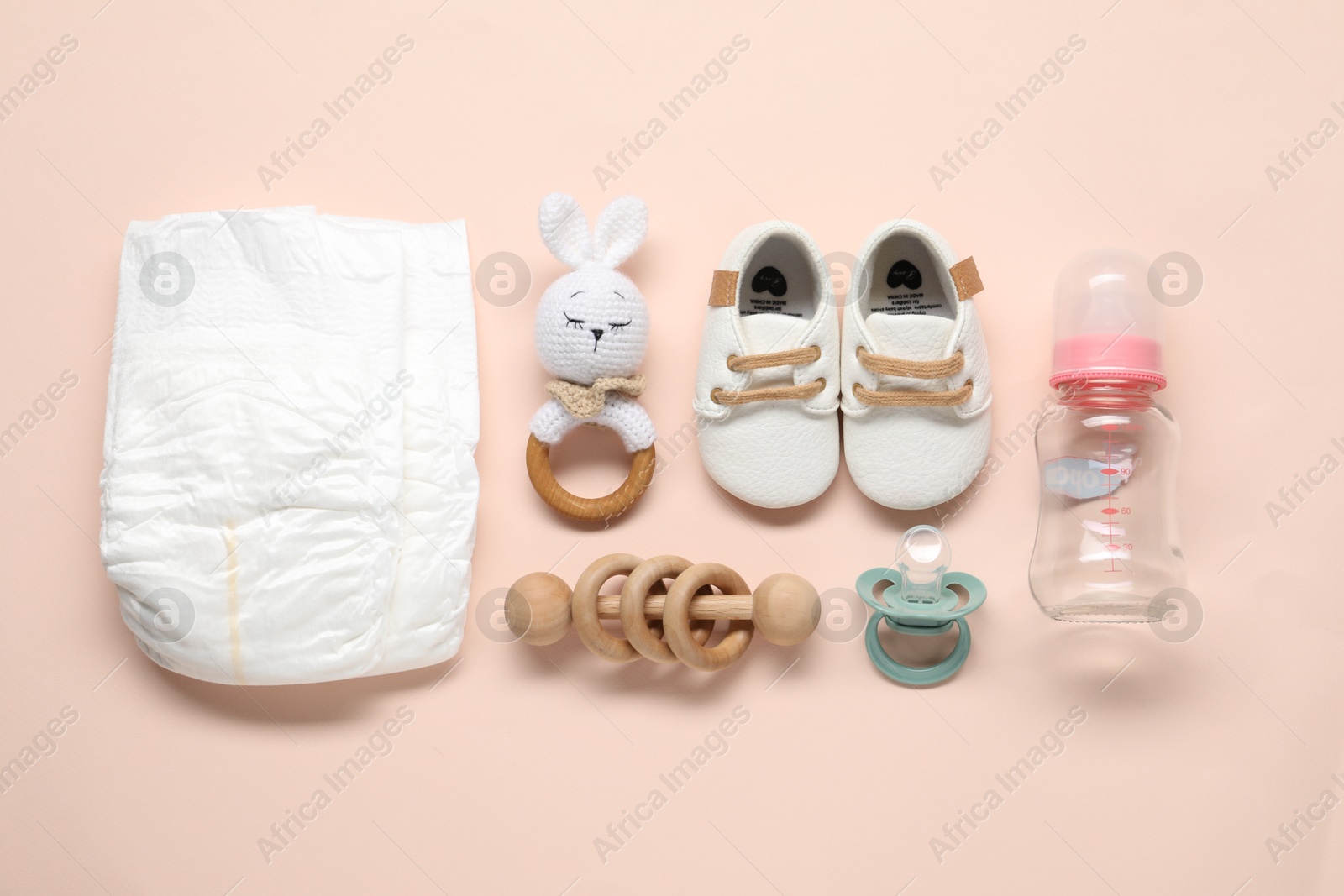 Photo of Baby rattles and accessories on light pink background, flat lay