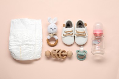 Baby rattles and accessories on light pink background, flat lay