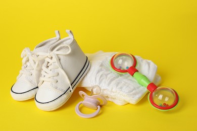 Photo of Baby rattle and accessories on yellow background