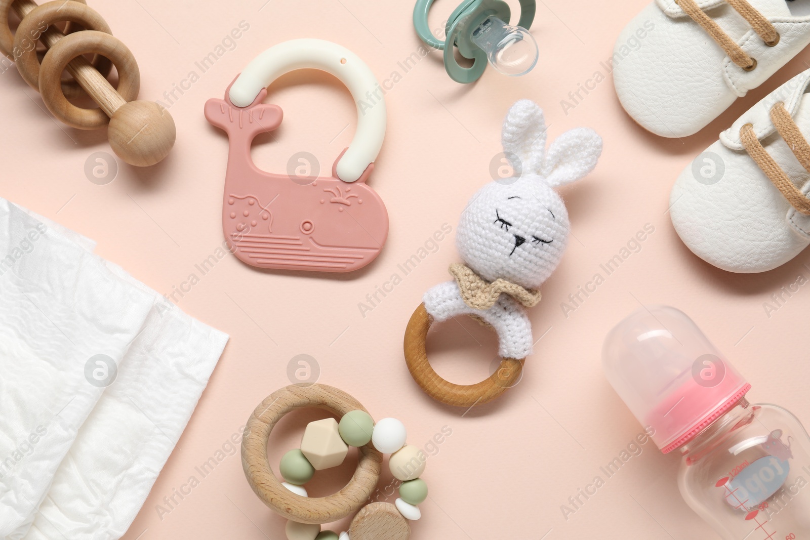 Photo of Baby rattles and accessories on light pink background, flat lay