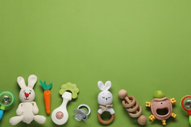 Photo of Different baby rattles on green background, flat lay. Space for text