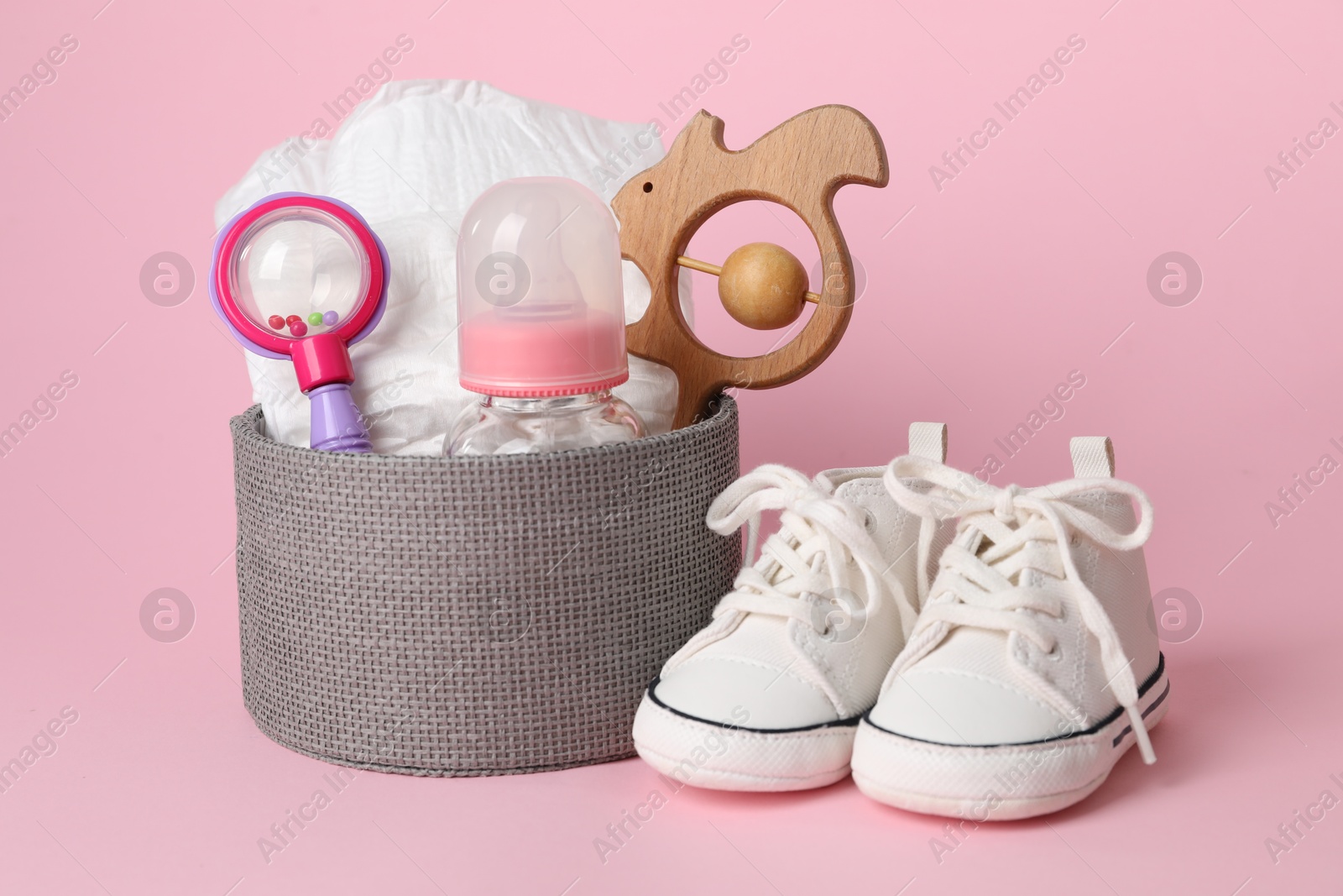 Photo of Box with different baby accessories on pink background