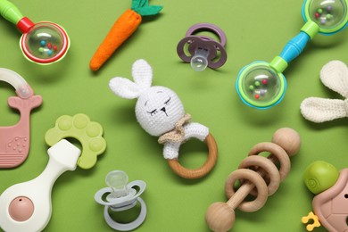 Photo of Different baby rattles on green background, flat lay