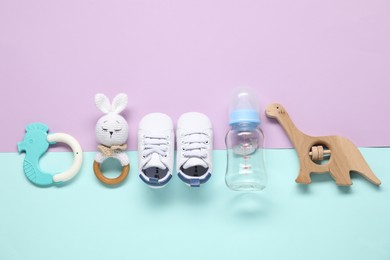 Photo of Baby rattles, teether, bottle and booties on color background, flat lay