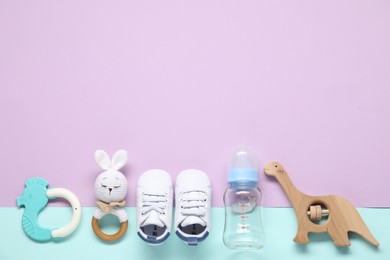 Photo of Baby rattles, teether, bottle and booties on color background, flat lay. Space for text