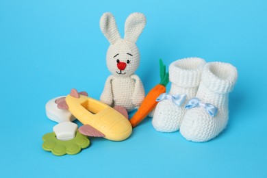 Baby toys and booties on light blue background