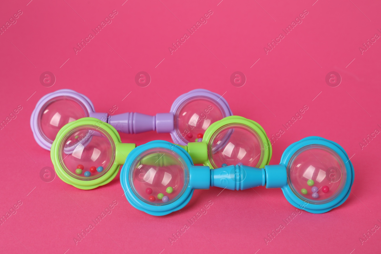 Photo of Three colorful baby rattles on crimson background