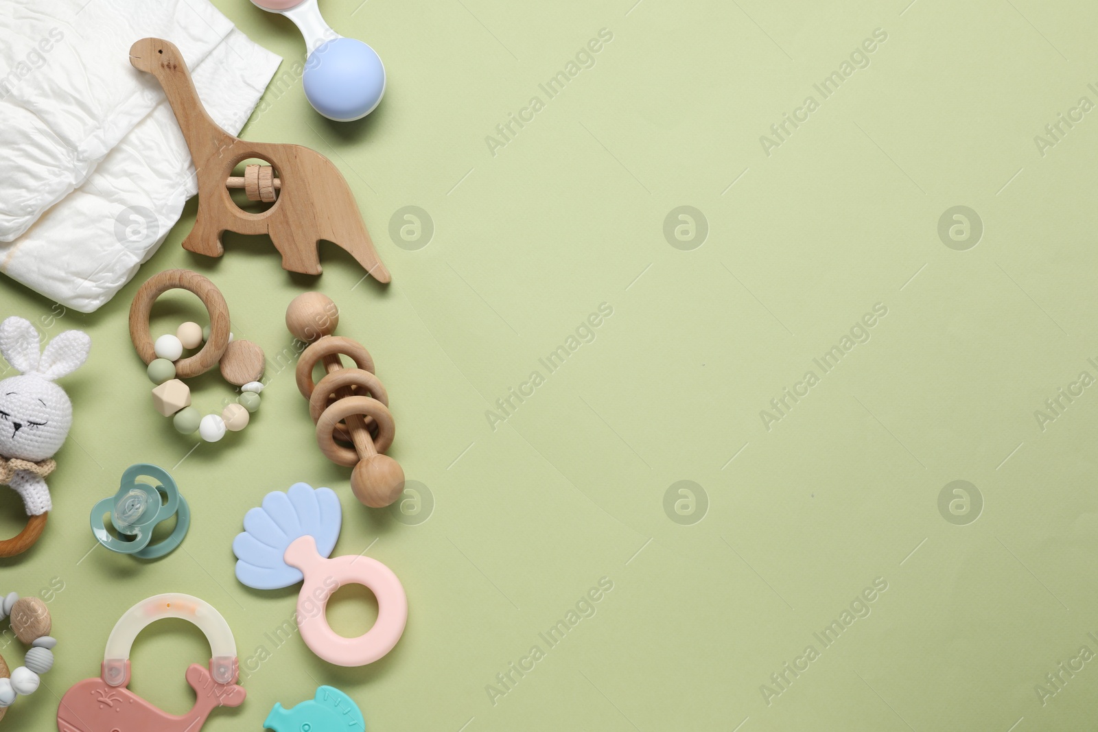 Photo of Different baby rattles and diapers on color background, flat lay. Space for text