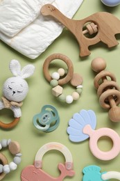 Different baby rattles and diapers on color background, flat lay