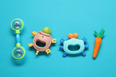 Different baby rattles on light blue background, flat lay