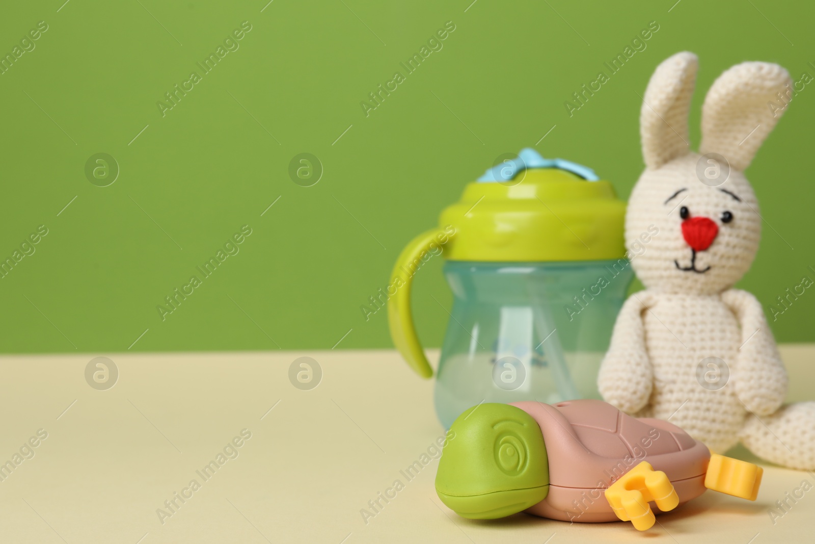 Photo of Baby toys and bottle on beige table. Space for text